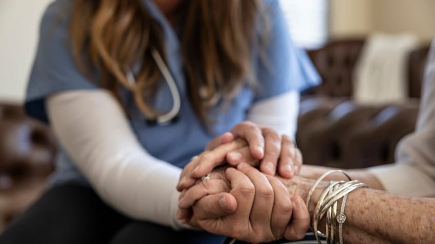 woman holding hands with older person