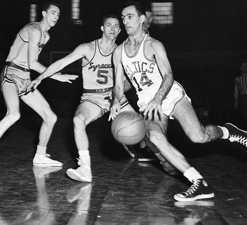 Bob Cousy of the Boston Celtics moves into score through Syracuse Men, Red Rocha and Paul Seymour , in the second quarter of the playoffs game at the...