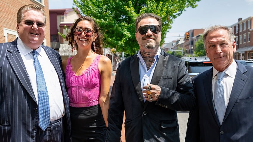 Bam Margera smiles outside court with his attorneys and fiancé Dannnii Marie