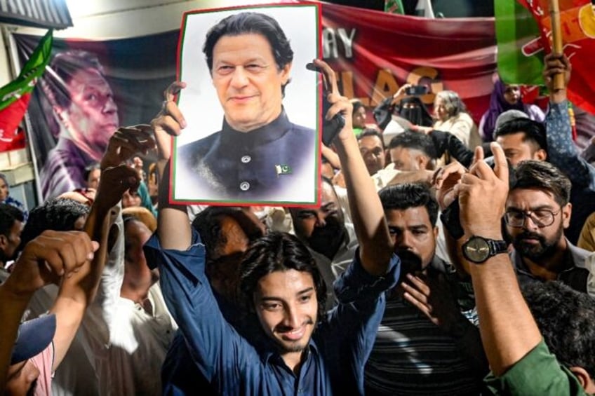 Supporters of Pakistan's jailed former prime minister Imran Khan hold his poster as they c