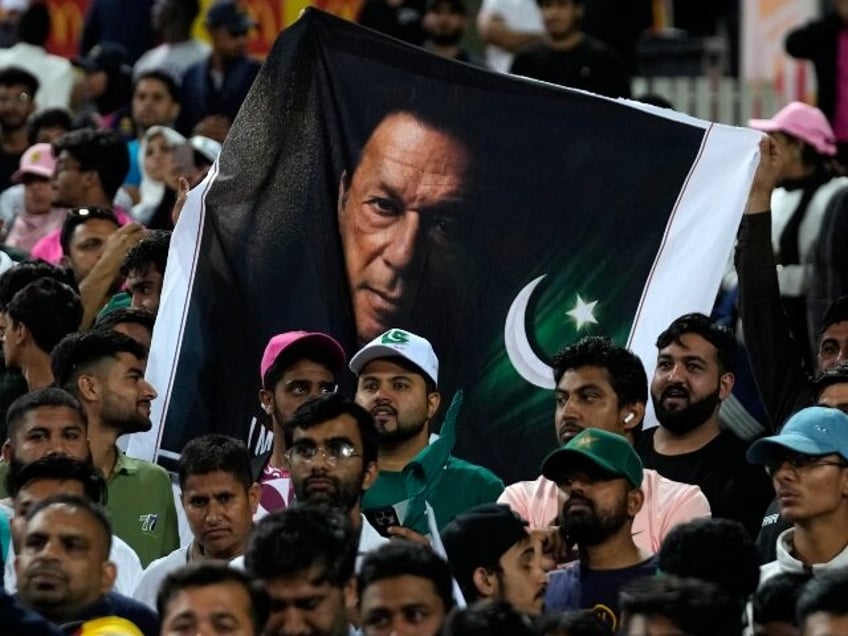 Pakistan's cricket fans hold a poster with imprisoned former premier Imran Khan follo