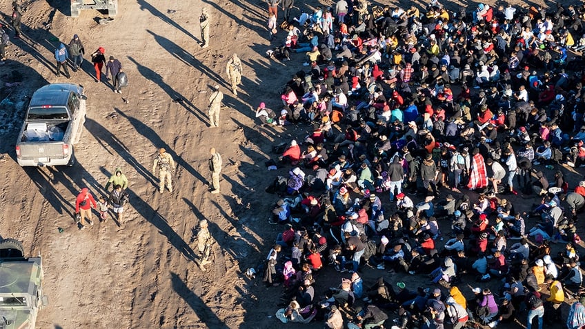 As seen from an aerial view, Texas National Guard troops watch over more than 1,000 immigrants who had crossed the Rio Grande overnight from Mexico on December 18, 2023 in Eagle Pass, Texas. (Photo by John Moore/Getty Images)