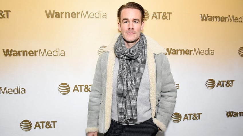 James Van Der Beek in a grey jacket with sherling trim and dark grey scarf looks serious on the carpet