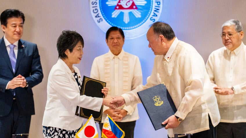 Japan Foreign Minister Yoko Kamikawa and Philippine Defense Secretary Gilberto Teodoro shake hands