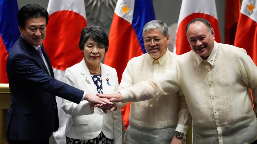 From left, Japan Defense Minister Minoru Kihara, Japan Foreign Minister Yoko Kamikawa, Philippines' Foreign Secretary Enrique Manalo and Philippines' Defense Secretary Gilberto Teodoro Jr. join hands