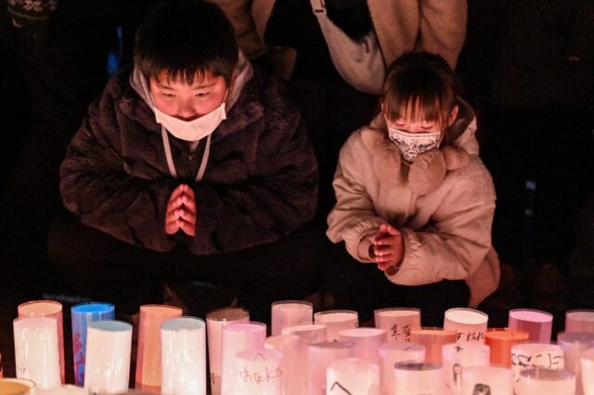 Children pray during an early morning ceremony to remember the victims on the 30th anniver