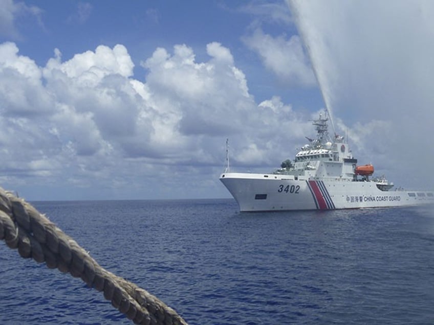 FILE - In this Sept. 23, 2015, file photo, Chinese Coast Guard members approach Filipino fishermen as they confront each other off Scarborough Shoal in the South China Sea, also called the West Philippine Sea. The Philippine defense chief says aerial surveillance shows Chinese coast guard ships are still guarding a disputed shoal but Filipinos were seen fishing there "unmolested" for the first time in years. Defense Secretary Delfin Lorenzana said Sunday, Oct. 30, 2016, the return of Filipino fishermen to Scarborough Shoal was "a most welcome development." (AP Photo/Renato Etac, File)