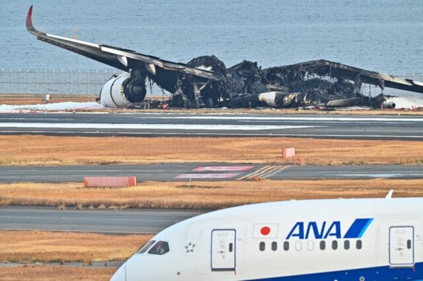 The burned-out wreckage of a Japan Airlines passenger plane sits on the tarmac at Tokyo's Haneda Airport