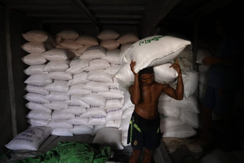 A labourer unloads sacks of rice from a ship at a jetty in Yangon. The price of rice in My