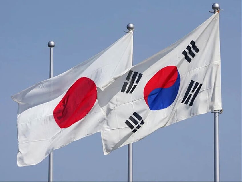 The national flags of Japan (L) and South Korea (R) flutter in the wind ahead of the arrival of South Koreas President Yoon Suk Yeol at Tokyo's Haneda Airport on March 16, 2023. - Yoon was set to arrive in Tokyo for a summit aimed at boosting ties in the …