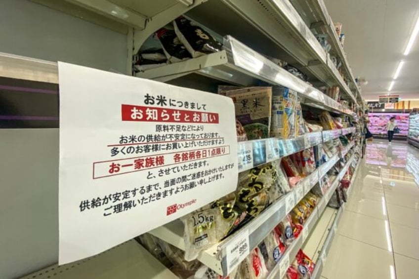 A supermarket in Tokyo has empty rice shelves and a sign telling customers they can only b