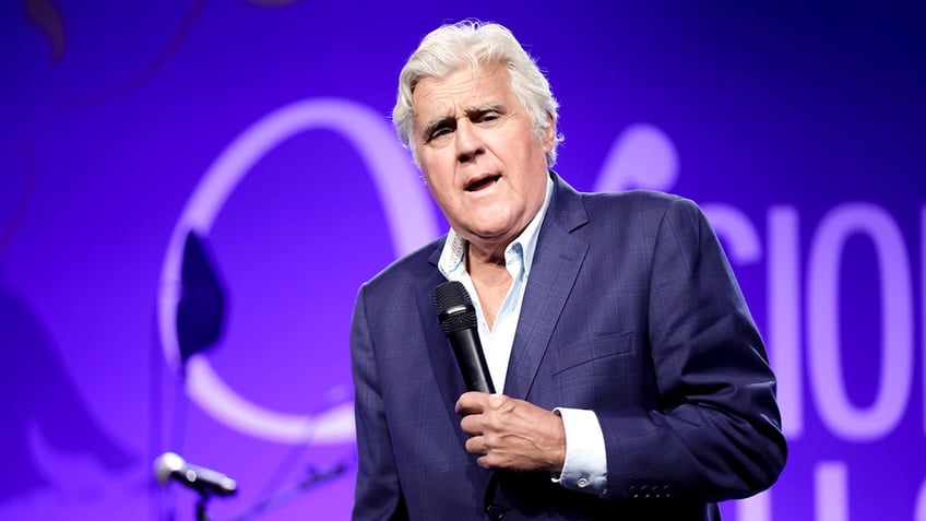 Jay Leno standing on stage with a microphone