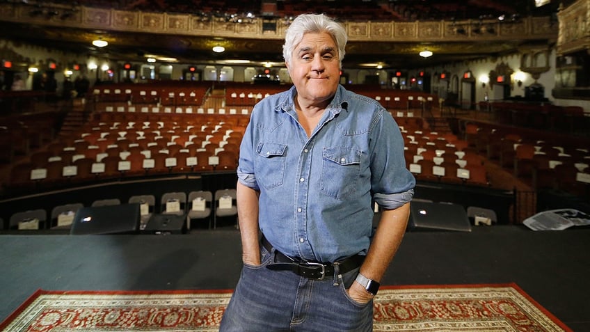 Jay Leno standing on stage in front of an empty theater