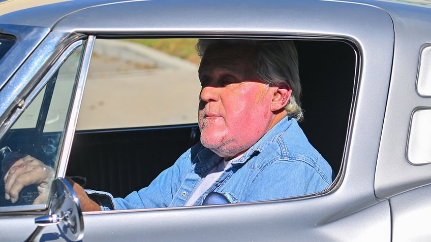 Jay Leno wearing denim driving his car shows off his relatively fresh burn on his cheek while driving in Los Angeles