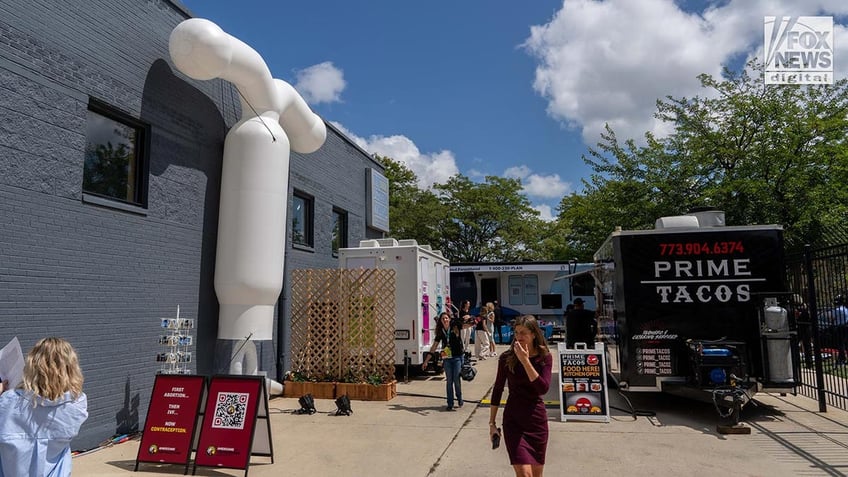 A taco truck, portable toilets and an abortion van parked beside a buiding