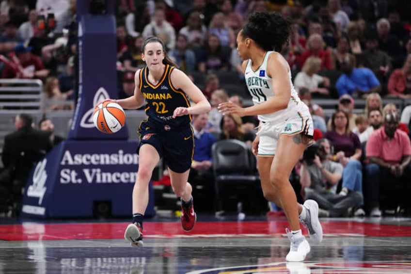 Caitlin Clark of the Indiana Fever dribbles the ball while being guarded by Betnijah Laney-Hamilton of the New York Liberty in the fourth quarter at...