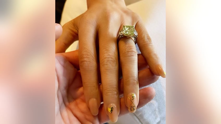 A picture of Jennifer Lopez's hand with her green diamond engagement ring and the letters 'B' and 'J' on her fingernails