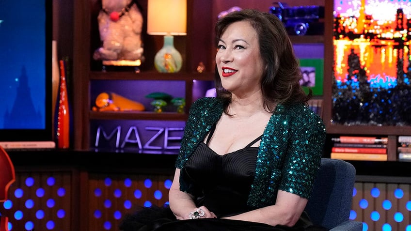 Jennifer Tilly sitting and smiling on the set of Watch What Happens Live