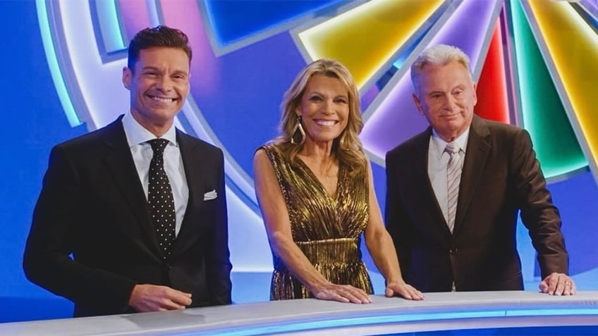 Ryan Seacrest smiles for a photo with Vanna White and Pat Sajak on the set of 'Wheel of Fortune'