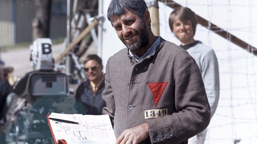 Jerry Lewis behind the scenes holding a script smiling with a film crew behind him