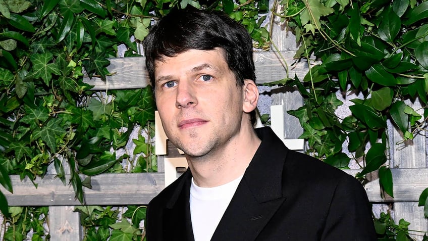 jesse eisenberg standing in front of an ivy background