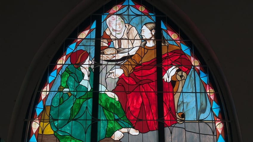 A stained glass window of Jesus, Mary, and Martha.