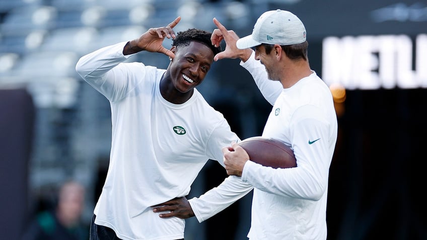 Aaron Rodgers and Sauce Gardner warm up