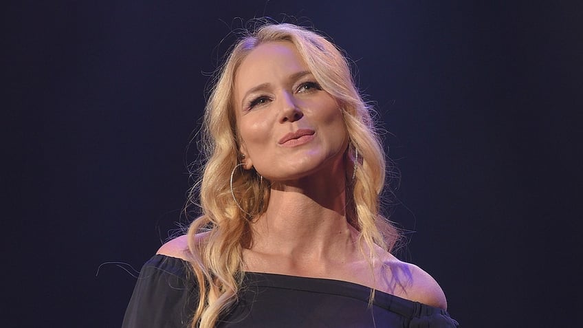 Singer Jewel wears an off the shoulder grey dress during a concert.