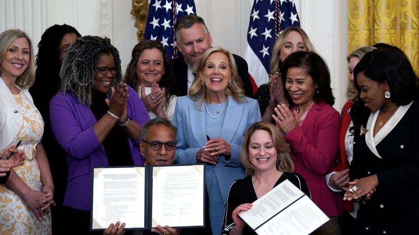 Supporters cheer as Deputy Secretary of Defense Kathleen Hicks and Deputy Secretary of State Richard Verma sign a permanent memorandum of agreement between Defense Department and State Department to strengthen the Domestic Employees Teleworking Overseas (DETO) program for military spouses in the East Room at the White House.