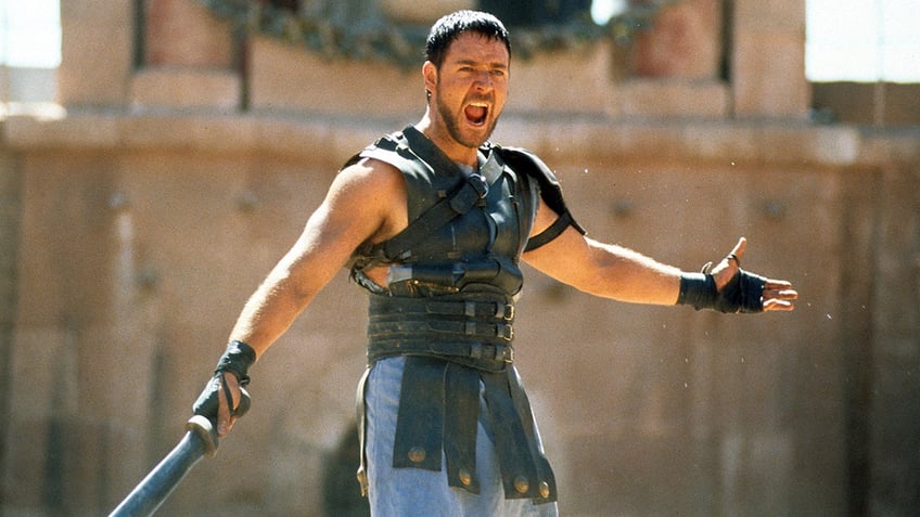 Russel Crowe yells with body armor on holding a sword in a scene from "Gladiator"