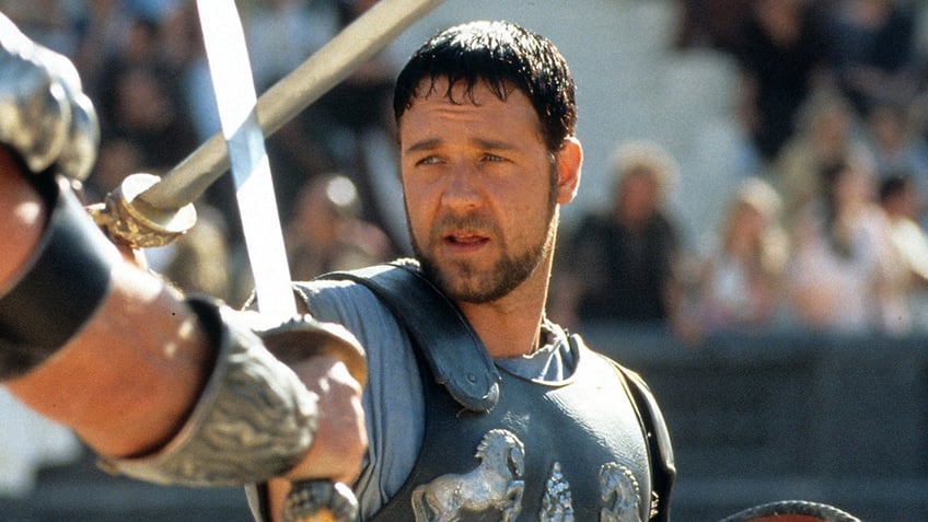 Russell Crowe in "Gladiator" with armor on holding up a sword, close up of his face