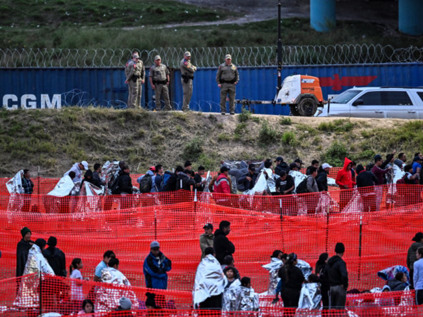 Customs and Border Protection agents stand guard as immigrants wait to be processed at a US Border Patrol transit center after crossing the border from Mexico at Eagle Pass, Texas, on December 22, 2023. Faced with the daily arrival of thousands of migrants from Mexico, US states and federal border police are declaring themselves overwhelmed, a crisis that is exposing the Biden administration to heavy fire from its Republican opponents. In recent weeks, the border police have reported some 10,000 people crossing the border every day, an even faster pace than in previous months. The Republican governor of Texas signed a bill on December 18, 2023 that would allow state police to arrest and deport migrants who cross illegally into the United States from Mexico. (Photo by CHANDAN KHANNA / AFP) (Photo by CHANDAN KHANNA/AFP via Getty Images)