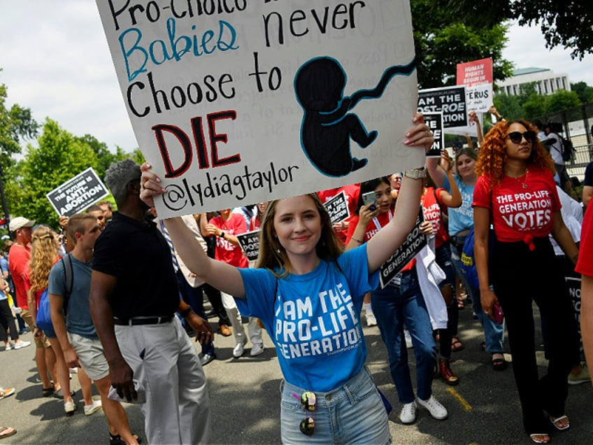 Anti-abortion campaigners celebrate near the US Supreme Court in the streets of Washington, DC, on June 24, 2022. - The US Supreme Court on Friday ended the right to abortion in a seismic ruling that shreds half a century of constitutional protections on one of the most divisive and bitterly fought issues in American political life. The conservative-dominated court overturned the landmark 1973 "Roe v Wade" decision that enshrined a woman's right to an abortion and said individual states can permit or restrict the procedure themselves. (Photo by OLIVIER DOULIERY / AFP) (Photo by OLIVIER DOULIERY/AFP via Getty Images)