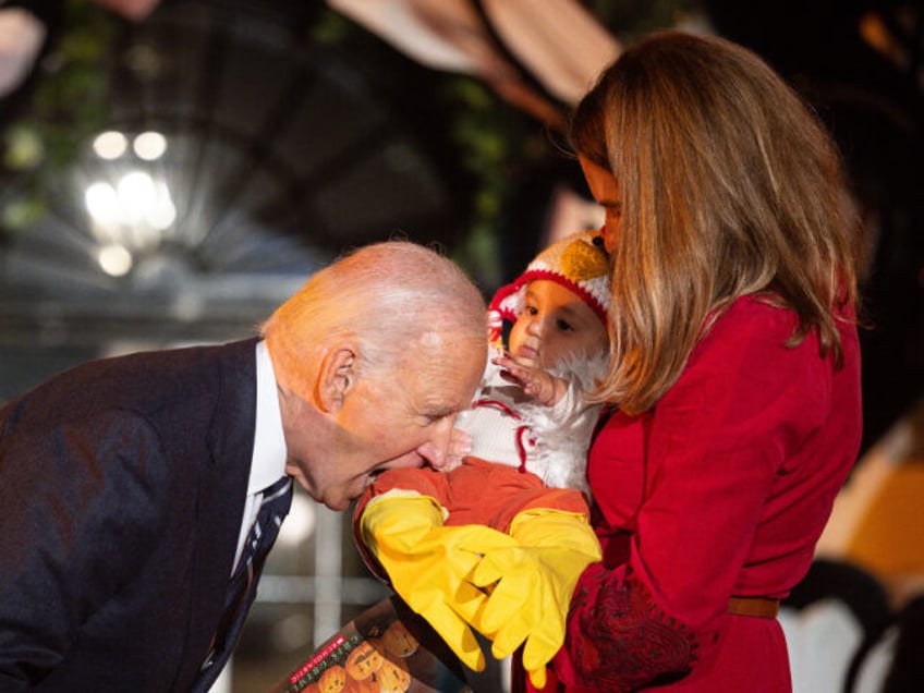 US President Joe Biden jokingly bites a baby dressed as a chicken as he hosts a Halloween