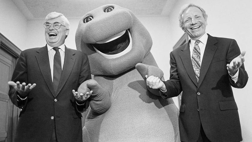 Former Sen. Christopher John "Chris" Dodd, D-Conn., and the late Sen. Joseph "Joe" Lieberman, D-Conn., play around at a promotional event for PBS in the Hart Senate Office Building, September 13, 1993, with Barney the Dinosaur.