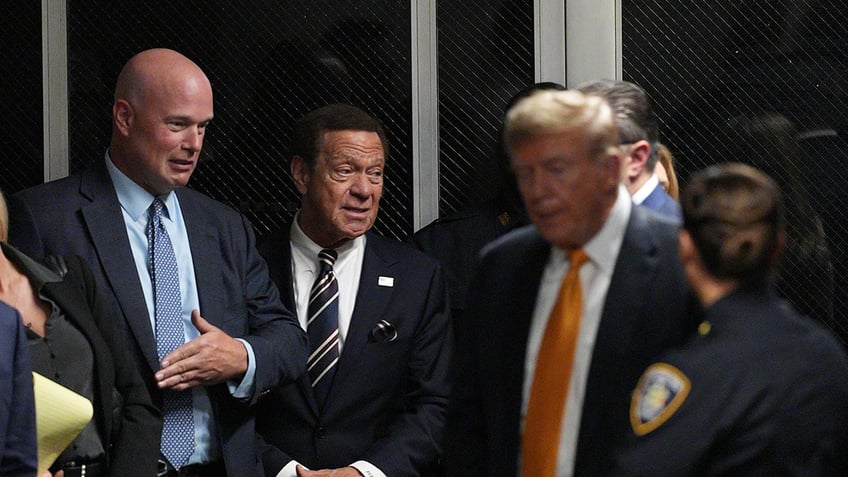 Joe Piscopo walking behind Trump entering a court room