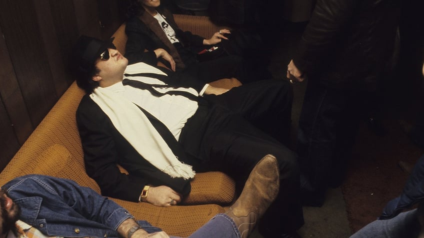 Blues brother John Belushi sits backstage after a show