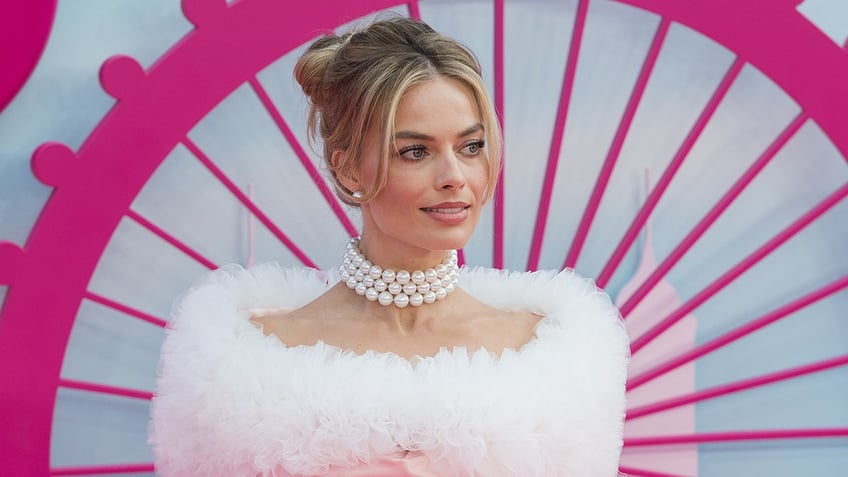 Margot Robbie wearing choker pearls and a light pink dress with a furry top