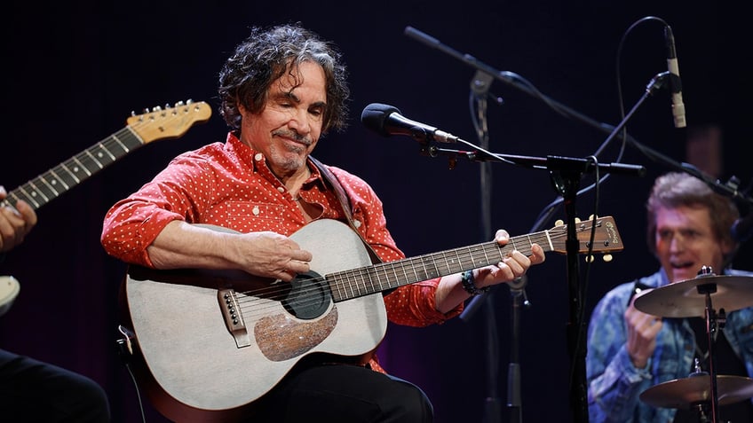 John Oates playing guitar on stage