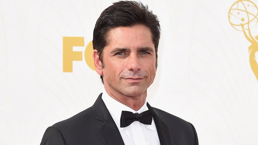 John Stamos in 2015 wearing a bowtie and black coat.