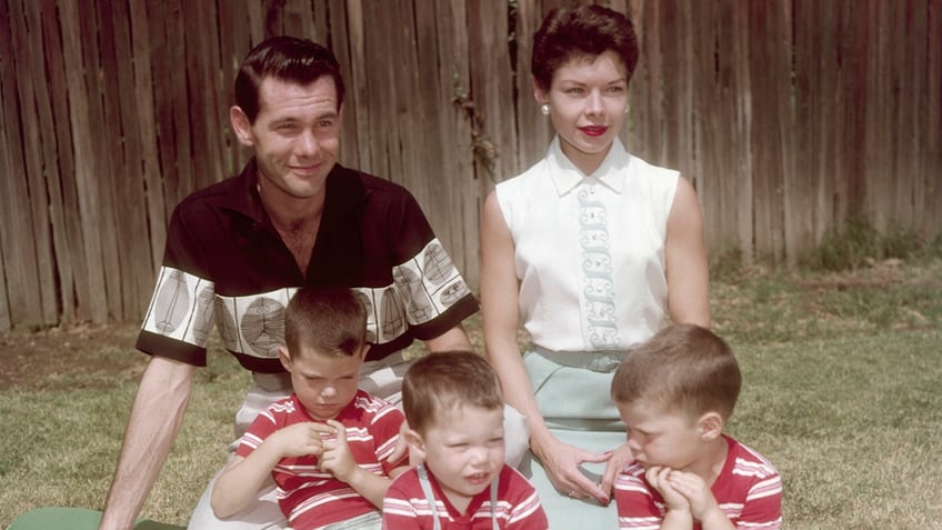 Johnny Carson and his wife Jody sitting together with their three sons wearing identical red striped outfits