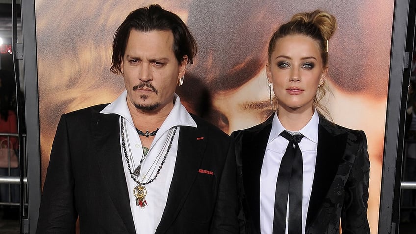 Johnny Depp and Amber heard wearing matching suits and looking serious on the red carpet.