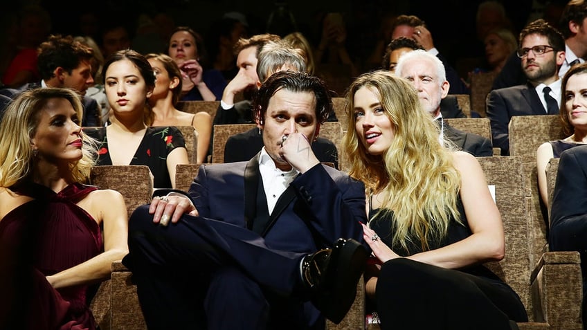 Amber Heard and Johnny Depp sitting front row at a movie theater.