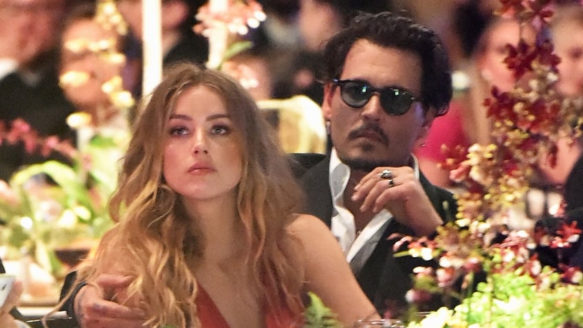 Amber Heard and Johnny Depp sitting together as they look serious.