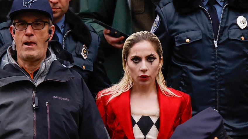 Lady Gaga in character for "Joker: Folie à Deux" wearing a red blazer and checkered shirt