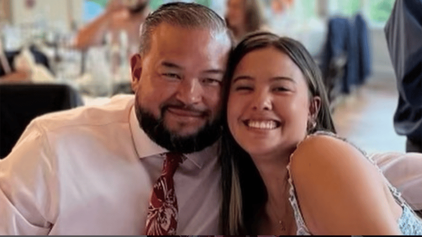 John Gosselin in a light pink shirt and patterned tie smiles next to Hannah Gosselin at a table