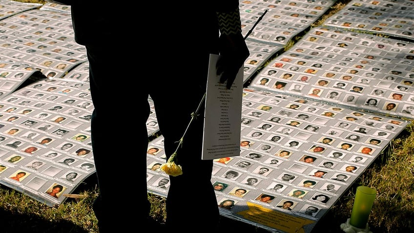 A man looking at a memorial of the dead from Jonestown.