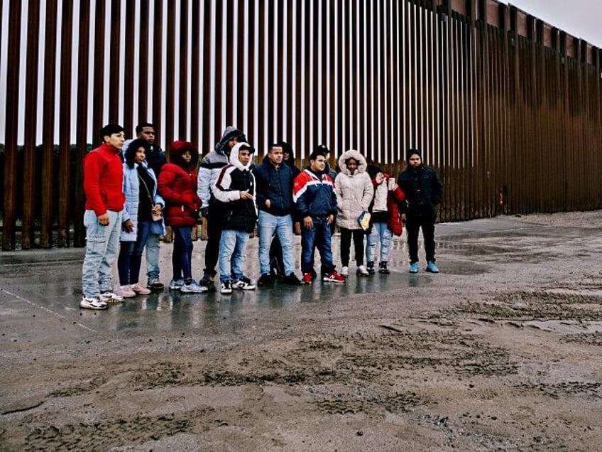 Migrants take a photograph while waiting to be transported for asylum claim processing at