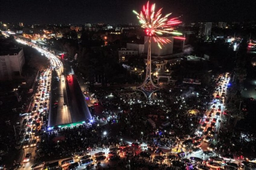 Fireworks erupt above people celebrating the ouster of Syrian president Bashar al-Assad at