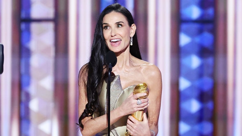 Actress Demi Moore smiles on stage with Golden Globe award